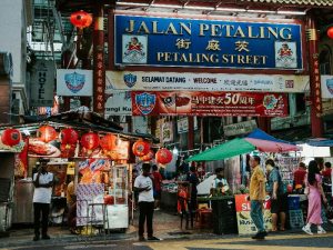 A street with people walking and a sign that says Petaling Street 