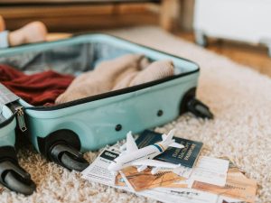 A luggage on the floor with personal belongings and a passport 